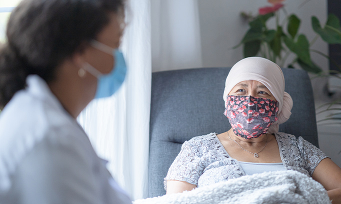 Pictured is a health care provider and cancer patient wearing a mask