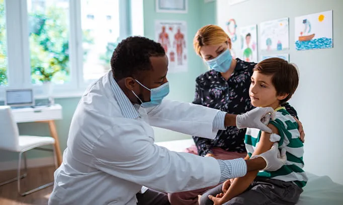 Doctor applying a bandage to a child's arm after getting their flu vaccine. 