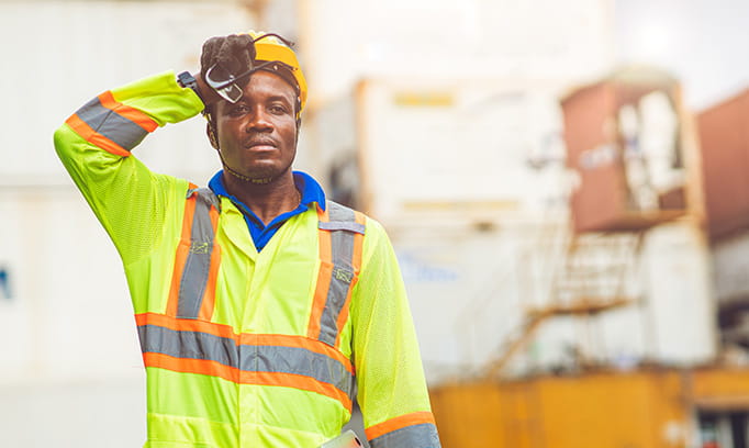 Construction worker at risk of heatstroke wiping sweat off their forehead on a hot day
