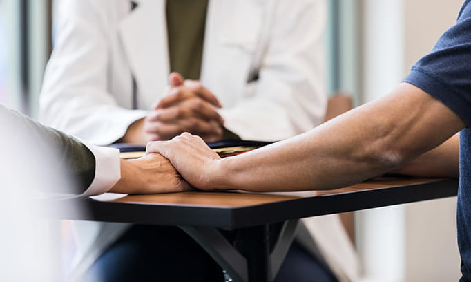 Two people sitting at a table learning about a cancer diagnosis at the first oncology appointment
