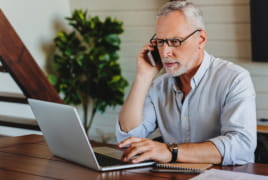 male at laptop on phone trying to figure out a bill