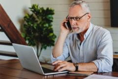 male at laptop on phone trying to figure out a bill