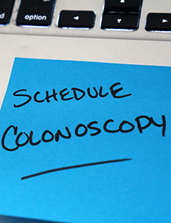 Sticky note with a handwritten reminder to schedule a colonoscopy.