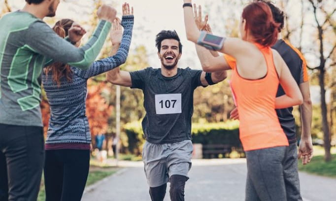 A man running a race, high-fiving his friends as he passed by them.