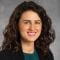 photo of rachelle damle, md - woman with brunette, curly hair wearing a green blouse and black suit jacket