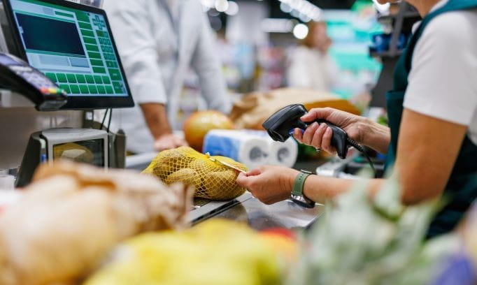 A grocery store clerk scanning a bag of potatoes at check-out.
