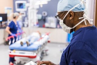 emergency doctor standing in trauma room with nurse and patient