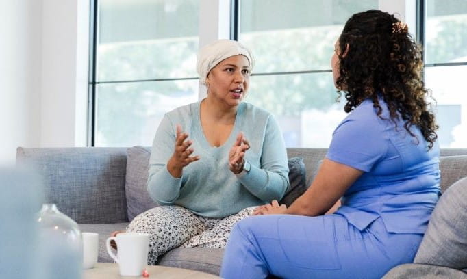 a woman sitting on a couch talking with her female doctor