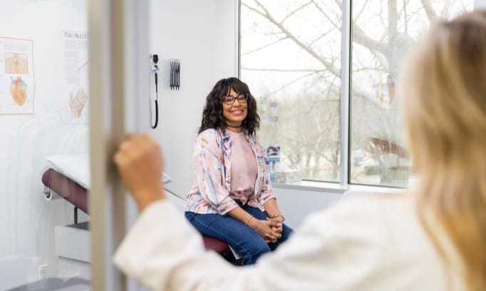 Doctor knocks on exam door to see patient waiting to be seen.
