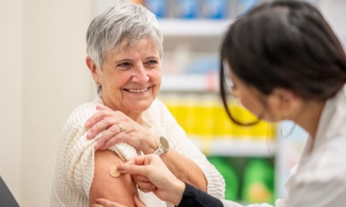 Doctor puts bandage on patients arm after receiving the flu shot.