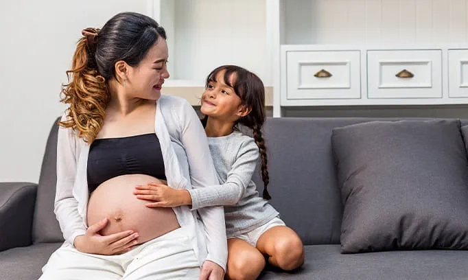 pregnant woman feels positive about her body and lets young girl touch her pregnant belly 