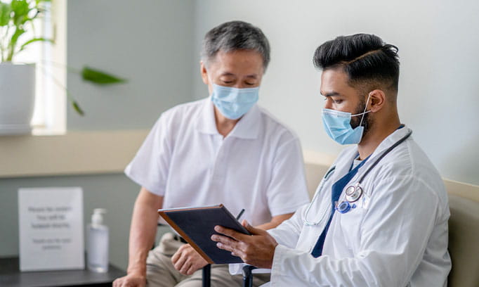Male health care provider explains patient education material to a patient focusing on health literacy