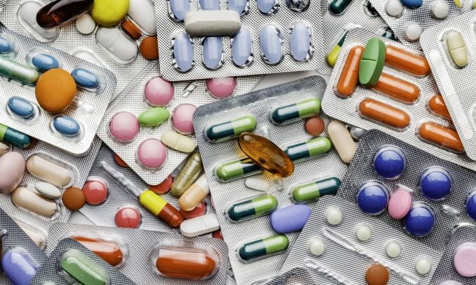 scattered pile of colorful pills in blister packs
