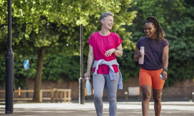 two women in athletic wear walking and happily conversing outdoors