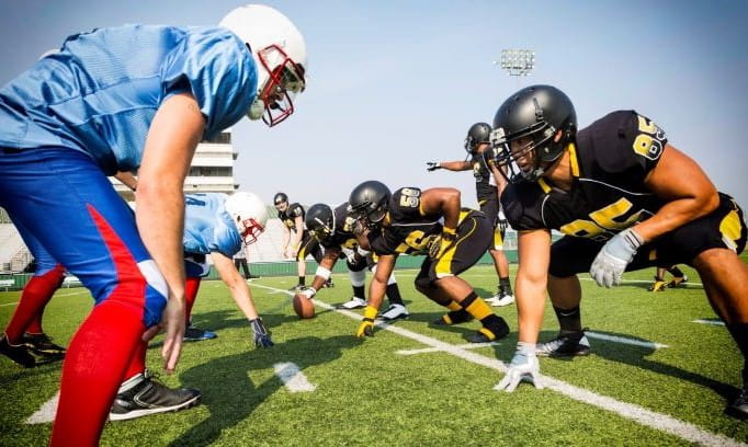 two high school football teams facing off at the line of scrimmage