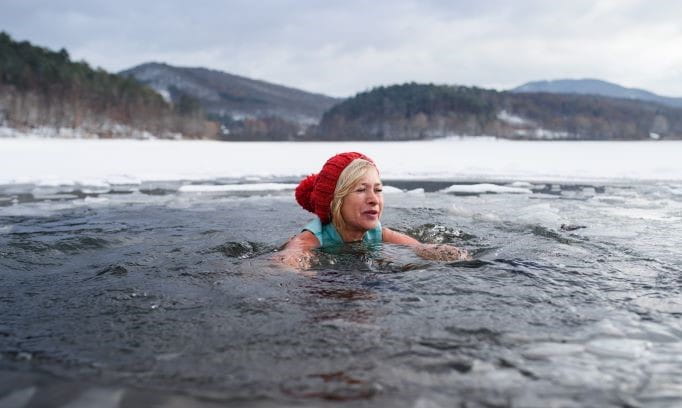 senior woman taking cold plunge in icy lake water
