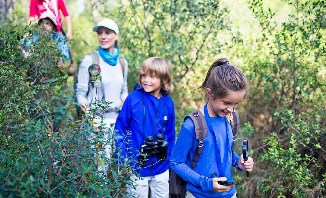 A family of five hiking on a trail wearing long sleeves and pants to avoid getting a tick bite and Lymes disease