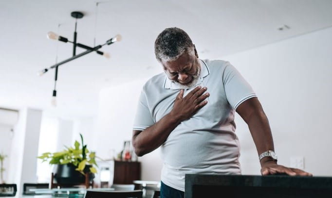 elderly man with palm on chest experiencing heart palpitations