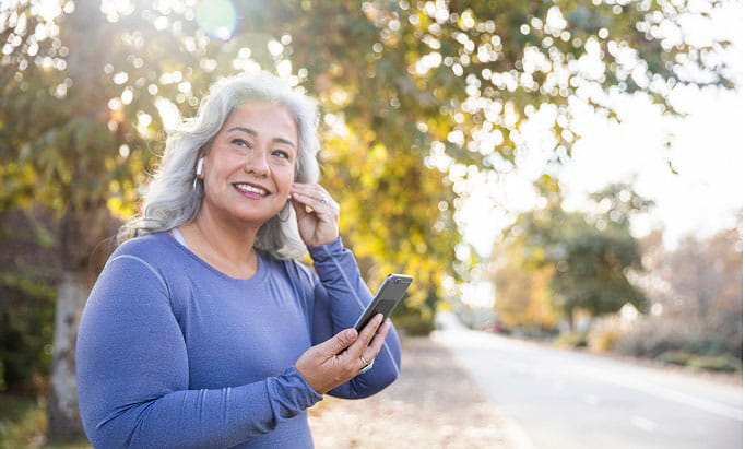 Woman putting in ear buds as she prepares to exercise for story about hearing loss