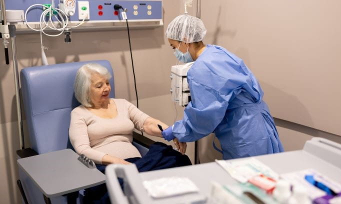 female patient in chair prepares for immunotherapy with her nurse