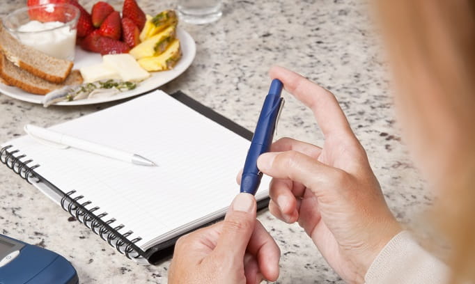 woman with diabetes at healthy breakfast pricks right index finger to check blood glucose levels for Insulin resistance 682x408