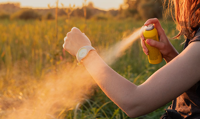 woman sprays insect repellent to prevent bug bites