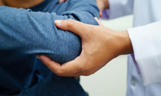 hand of ortho oncologist examining patient's elbow