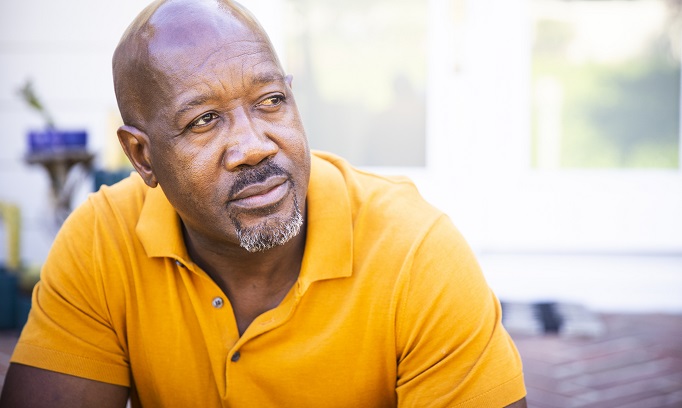 older black man wearing orange shirt wondering if he may have prostate cancer 682x408