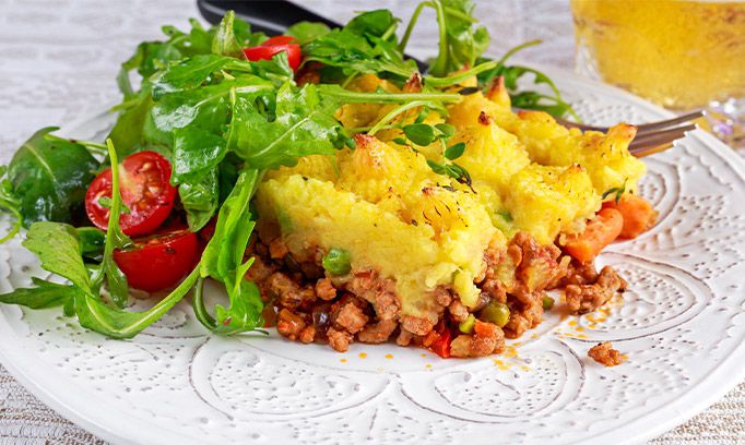 Shepherds pie with turkey and a green salad on a white plate