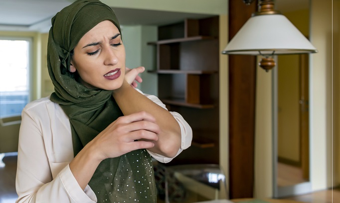 Woman in hajib scratching her arm from a stress rash 682x408