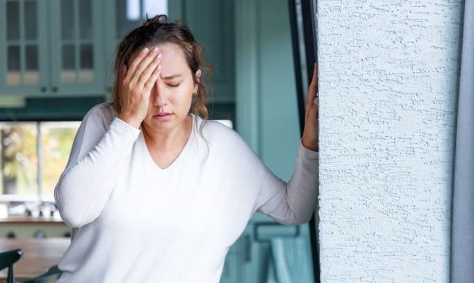 woman in pain holding hand to forehead while experiencing symptoms of a transient ischemic attack 