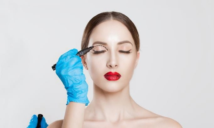 surgical gloved hand holding pen to mark upper eye lid for surgery