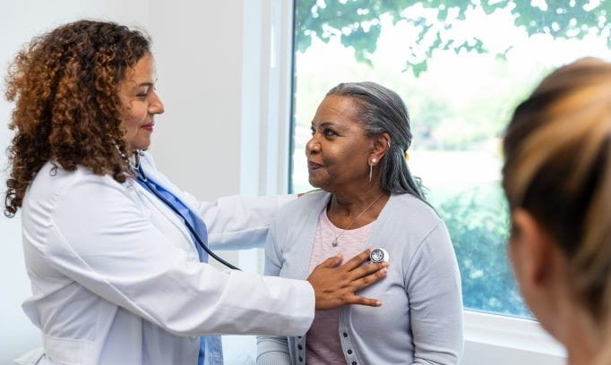 Female doctor listening to a senior woman's heart with a stethoscope in a medical clinic