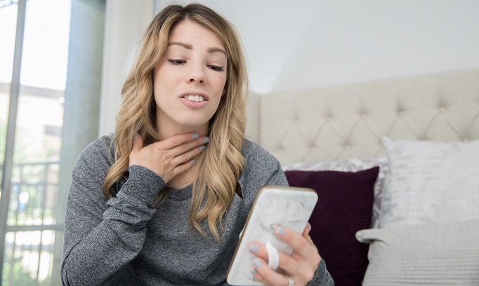 woman with sore throat seeks virtual care via her smart phone