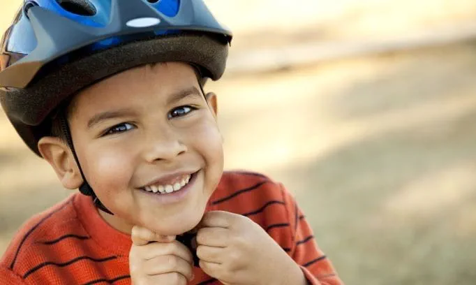 young boy buckling bike helmet on head