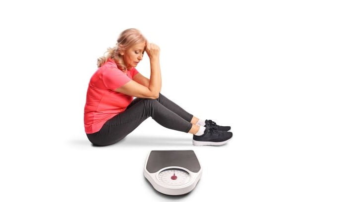 senior woman sitting near scale looking frustrated