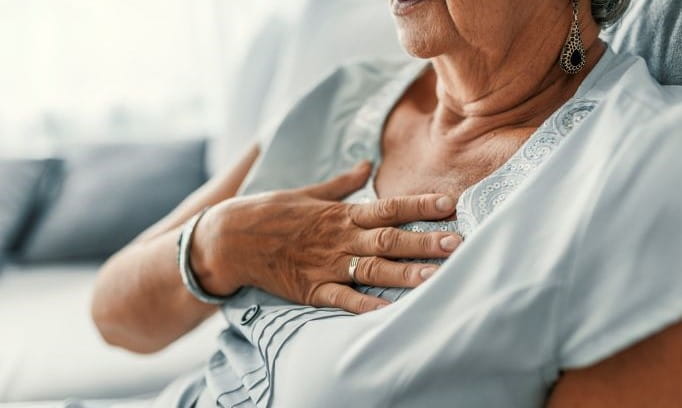 senior woman pressing on chest experiencing chest pains