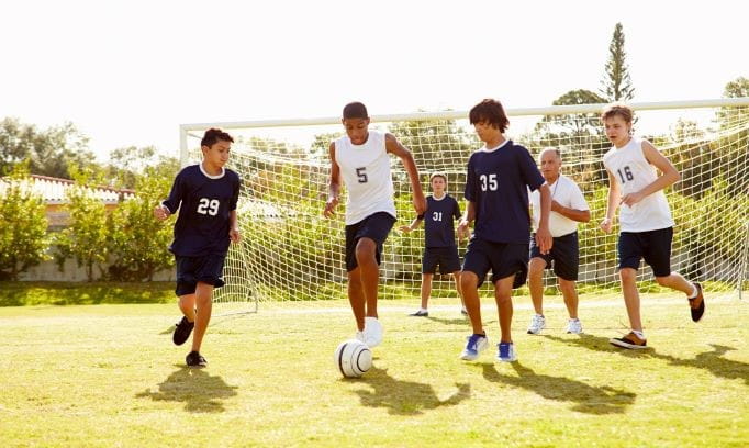 Teen athletes play soccer outside as they return to fall sports.