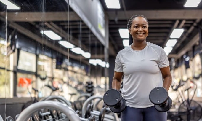 smiling woman picking up dumbbells in a fitness center