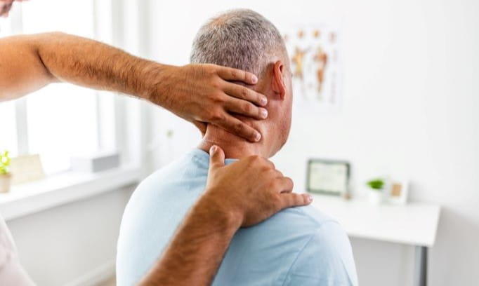 Male doctor examines an adult male's neck with his hands