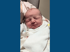 Newborn baby girl swaddled in mother's arms.