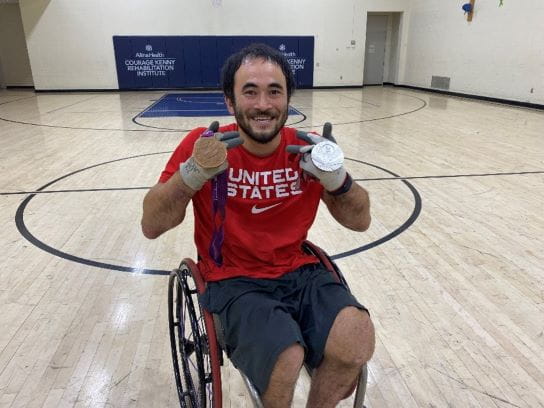 Photo of Chuck Aoki, member of Team USA's Paralympic rugby team, showing off his bonze and silver Paralympic medals.