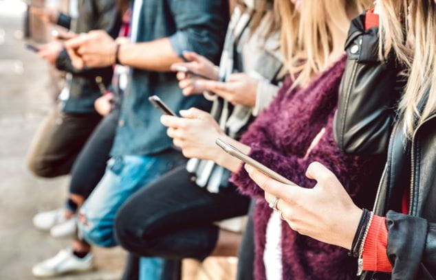 Close up of multiple teens on their phones using social media
