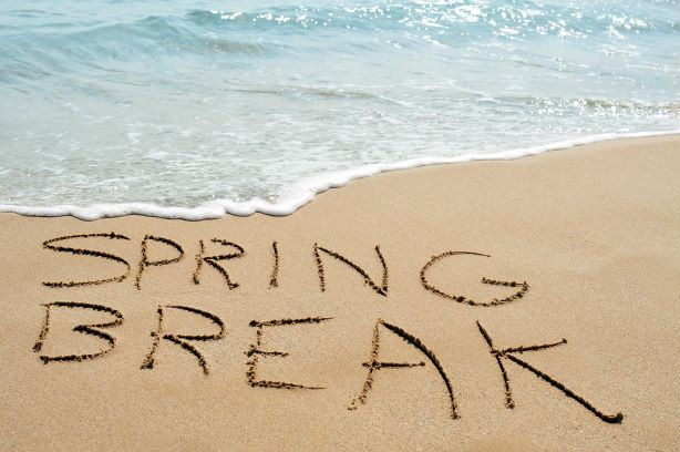 Spring break written on a white sandy beach next to the ocean